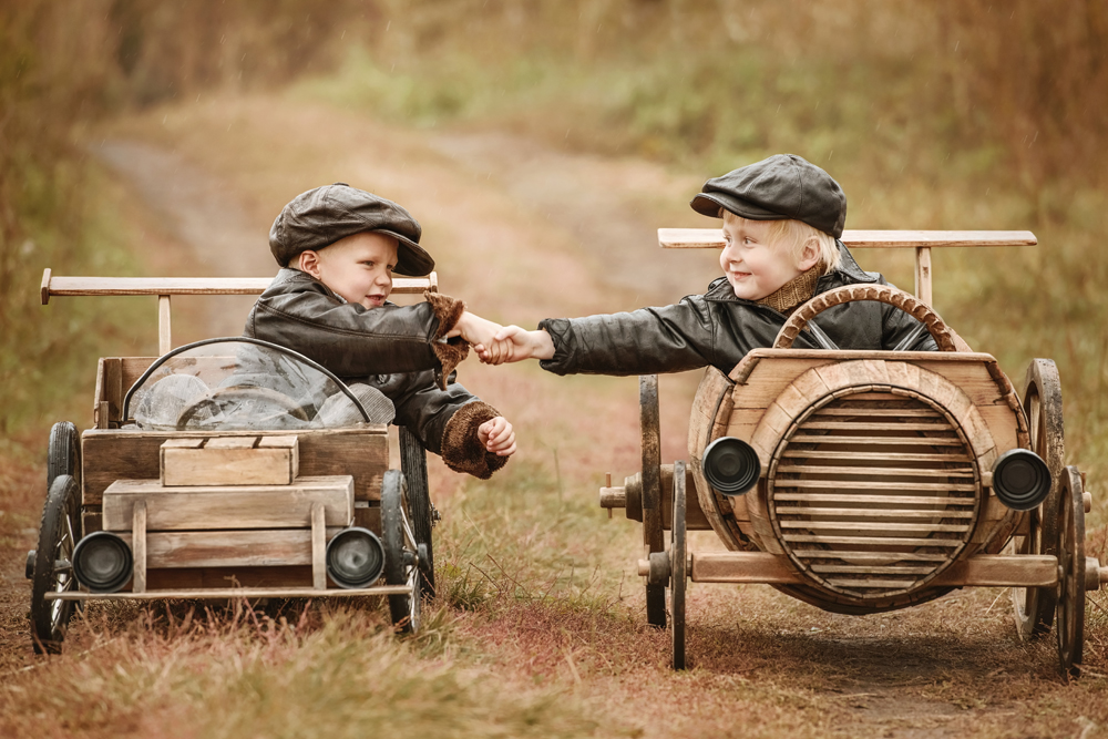 Handshake of two boys racers on their homemade wooden car. Retouch for retro